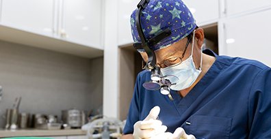 확대경과 별무늬 수술모자를 쓰고 시술하는 권장덕 원장